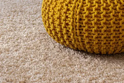 Yellow knitted bag on light colored carpet.