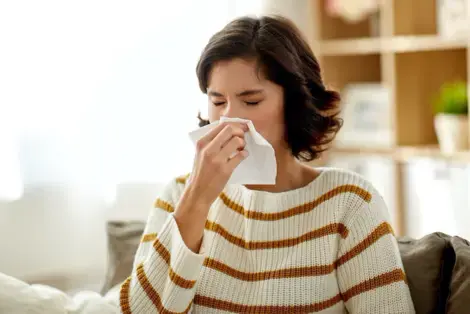 Woman in a striped shirt sneezing from HVAC Dust
