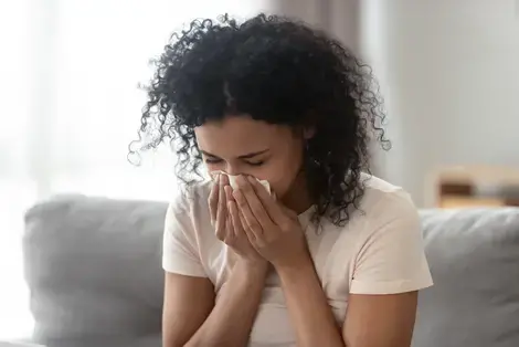 Woman sneezing due to allergies in the home.