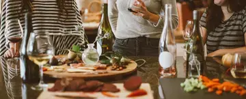 Three women in conversation around a table set for a Thanksgiving meal.