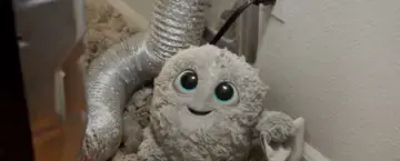 COIT IT logo mascot standing infront of a dryer vent