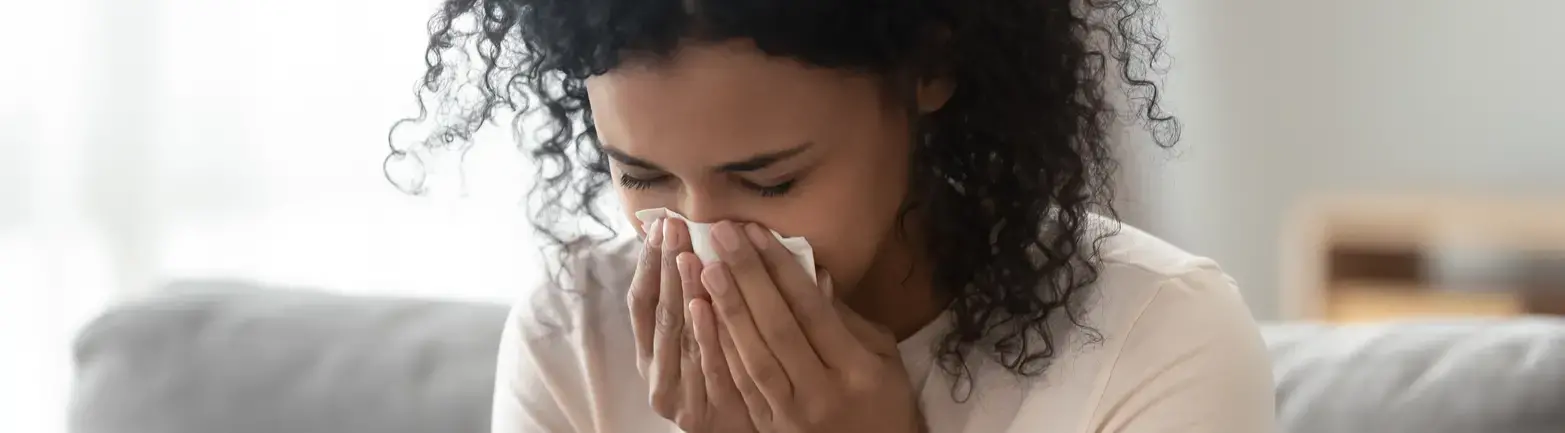 Woman sneezing due to allergies in the home.