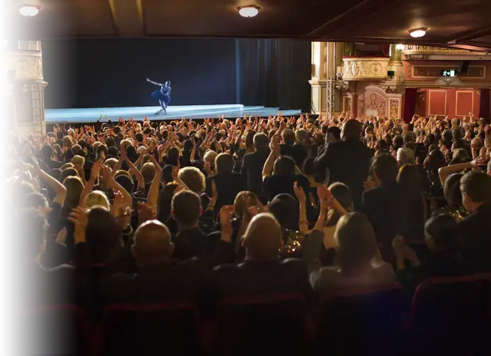 crowd sitting in a theater watching a performance on stage